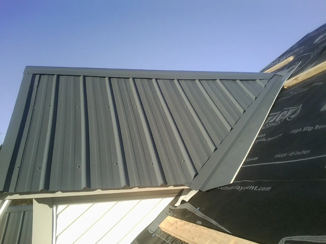 Gray metal roof panels going on over a garage gable in Cliffside Park