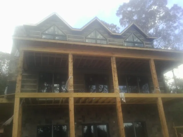 Dormers and porch framing on a large log home under construction — Roof Coating work by our crew in Cliffside Park