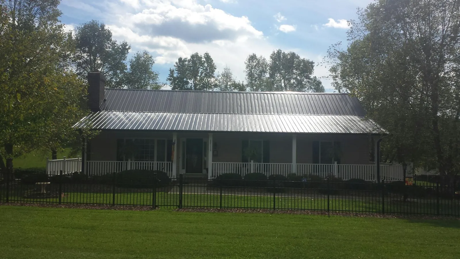 Gray metal roof on a brick ranch with a full width front porch — Gutter Guard Installation work by our crew in Cliffside Park
