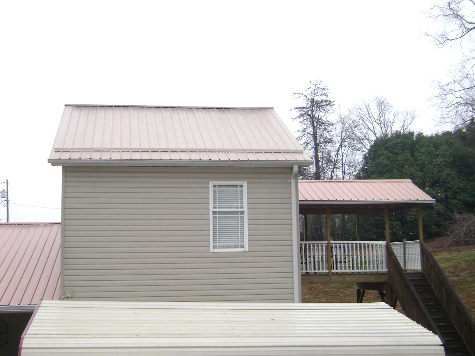 Tan metal roofs on a two story addition and attached porch, from a Roof Replacement job in Cliffside Park
