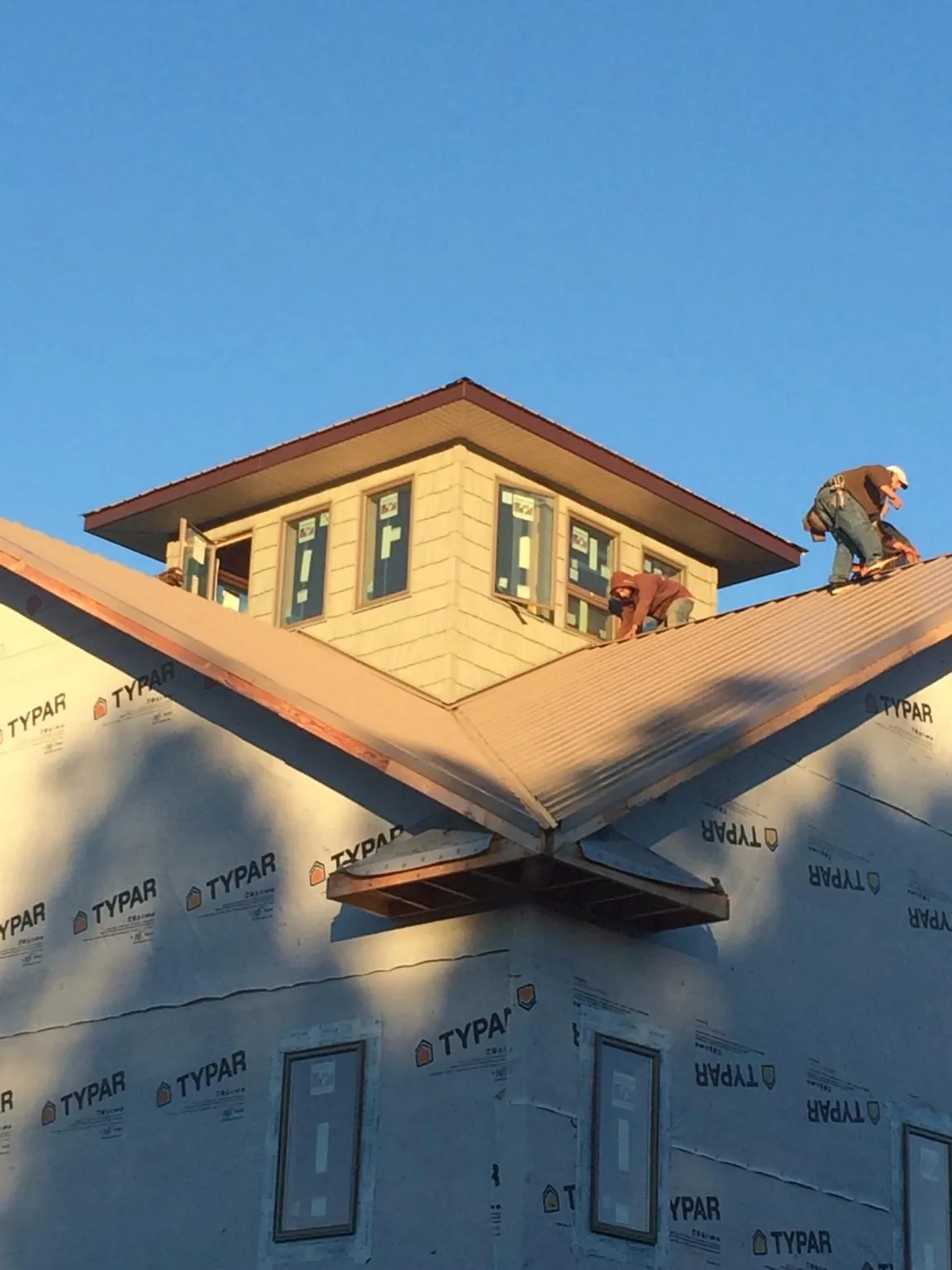 Roofers working around a rooftop cupola on a new metal roof at sunset — Roof Waterproofing in Cliffside Park by Roofing Brothers